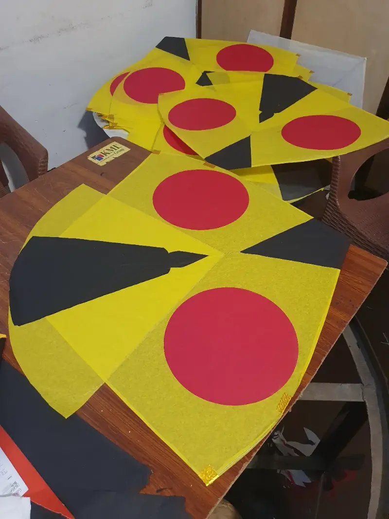 Yellow gudda kites with red circles and black panels on the workshop table at Lahore Kites Shop